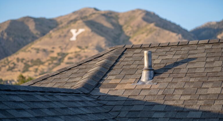 Close-up of a newly installed asphalt shingle roof and vent flashing on an Orem, Utah home with the Wasatch foothills behind
